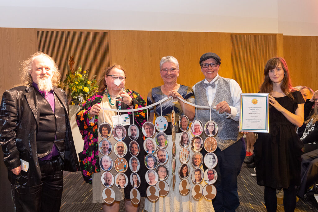 An image with the two award presenters surrounding three PREMIS EC members holding the tribute to all EC members in form of medallions with portraits and the DPC award and diploma.